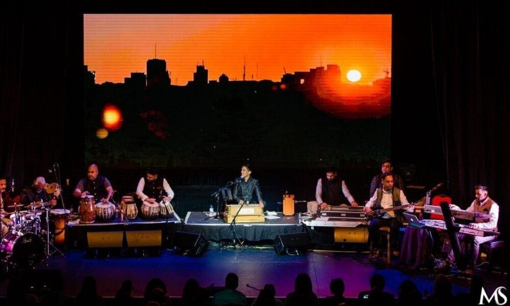 A percussion ensemble on a stage backed by a sunset filling the LED wall