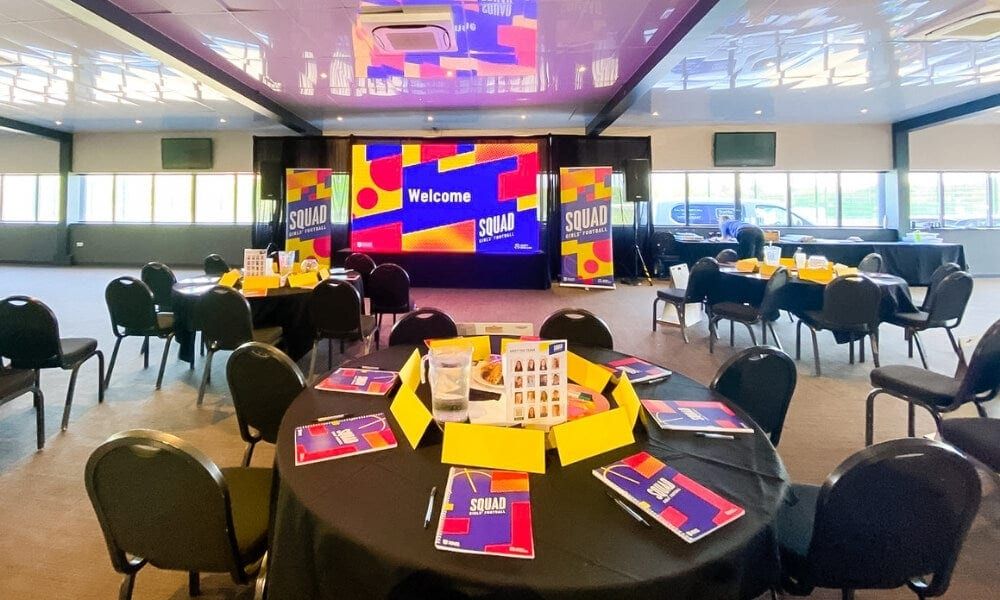 A conference room with branded screens and printed materials laid on round tables