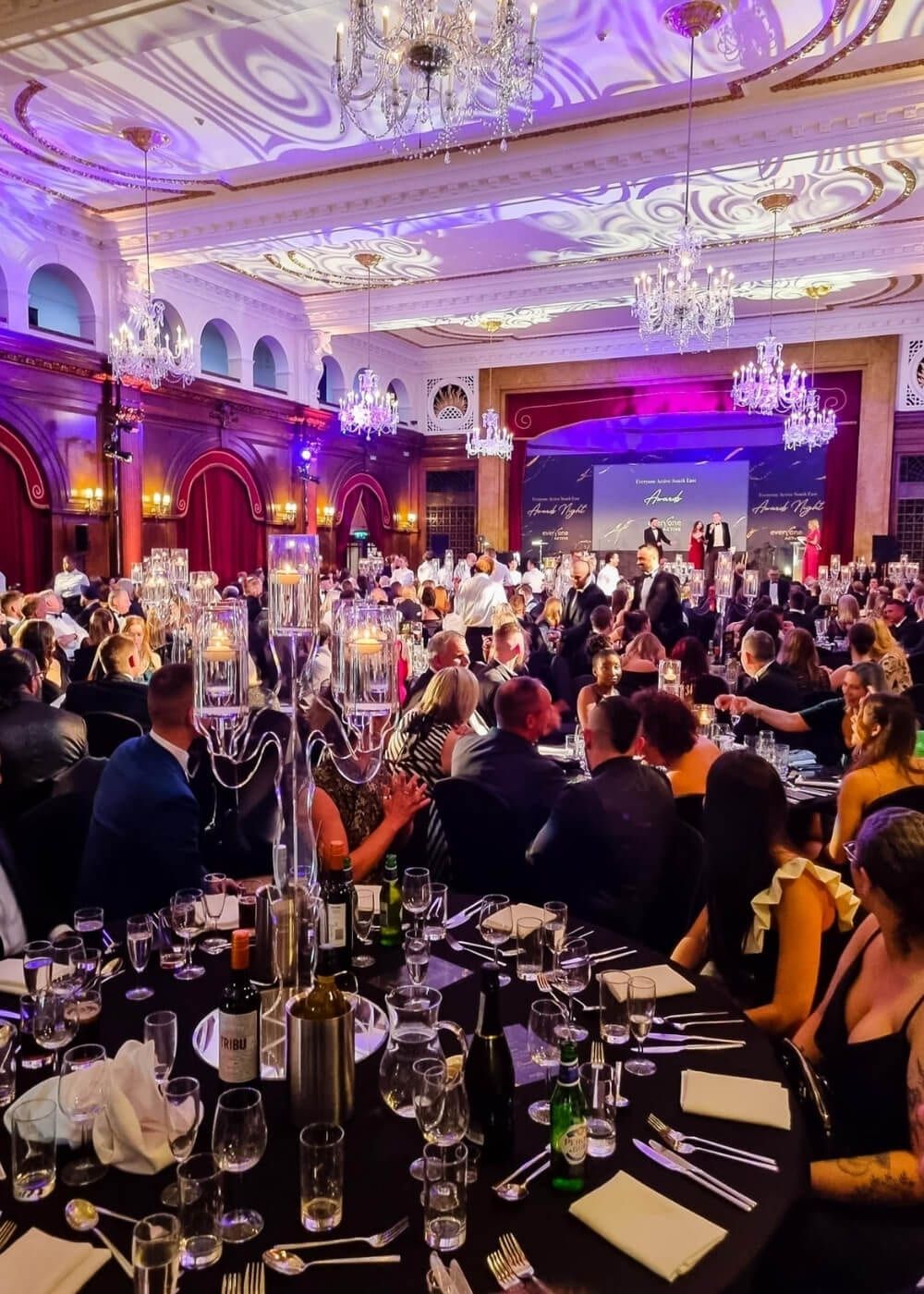 Guests seated at an awards dinner beneath chandeliers