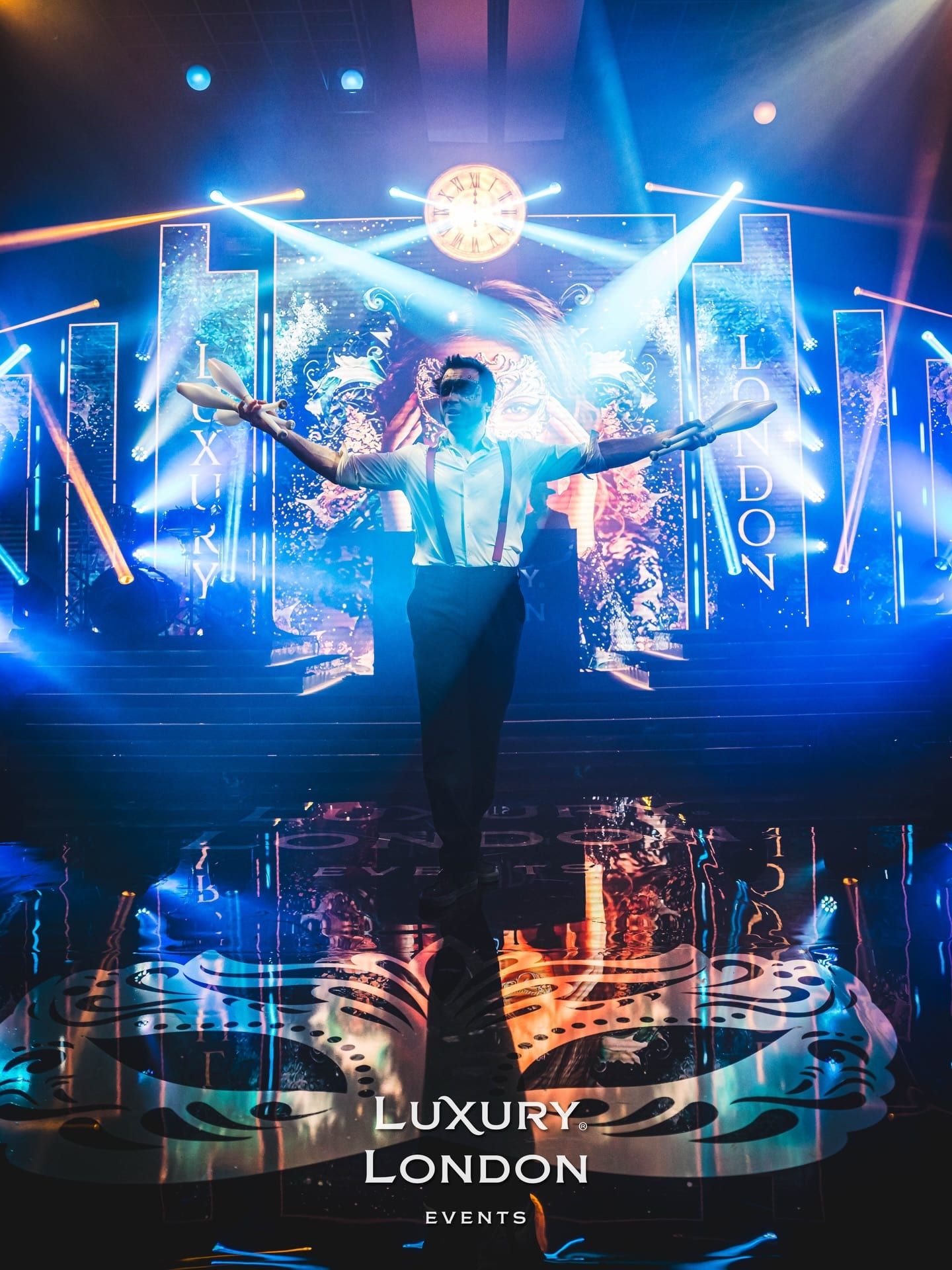 A performer on a stage backed by a blue LED wall, the floor mirroring the light