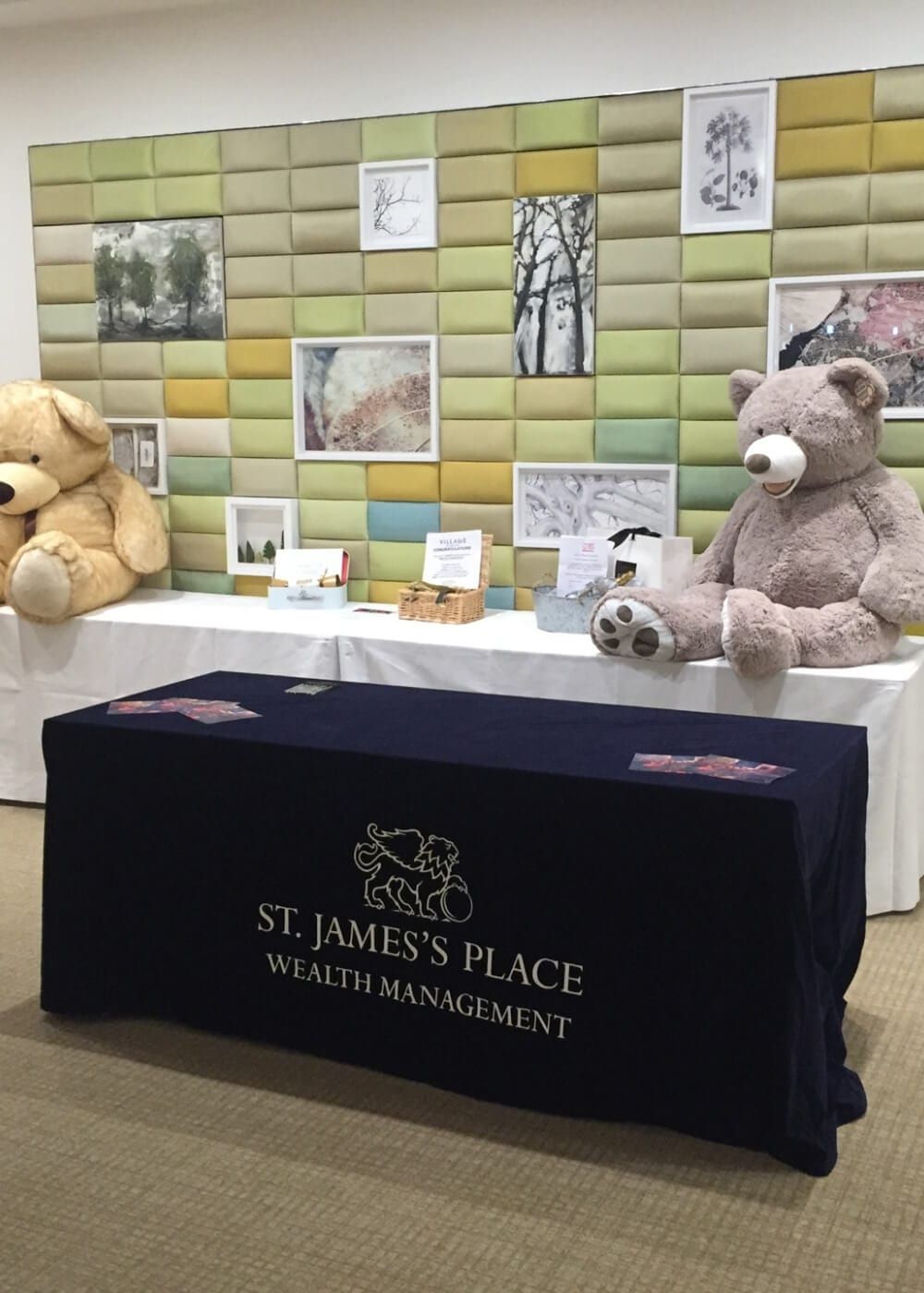 A charity stand dressed with teddy bears and a branded tablecloth