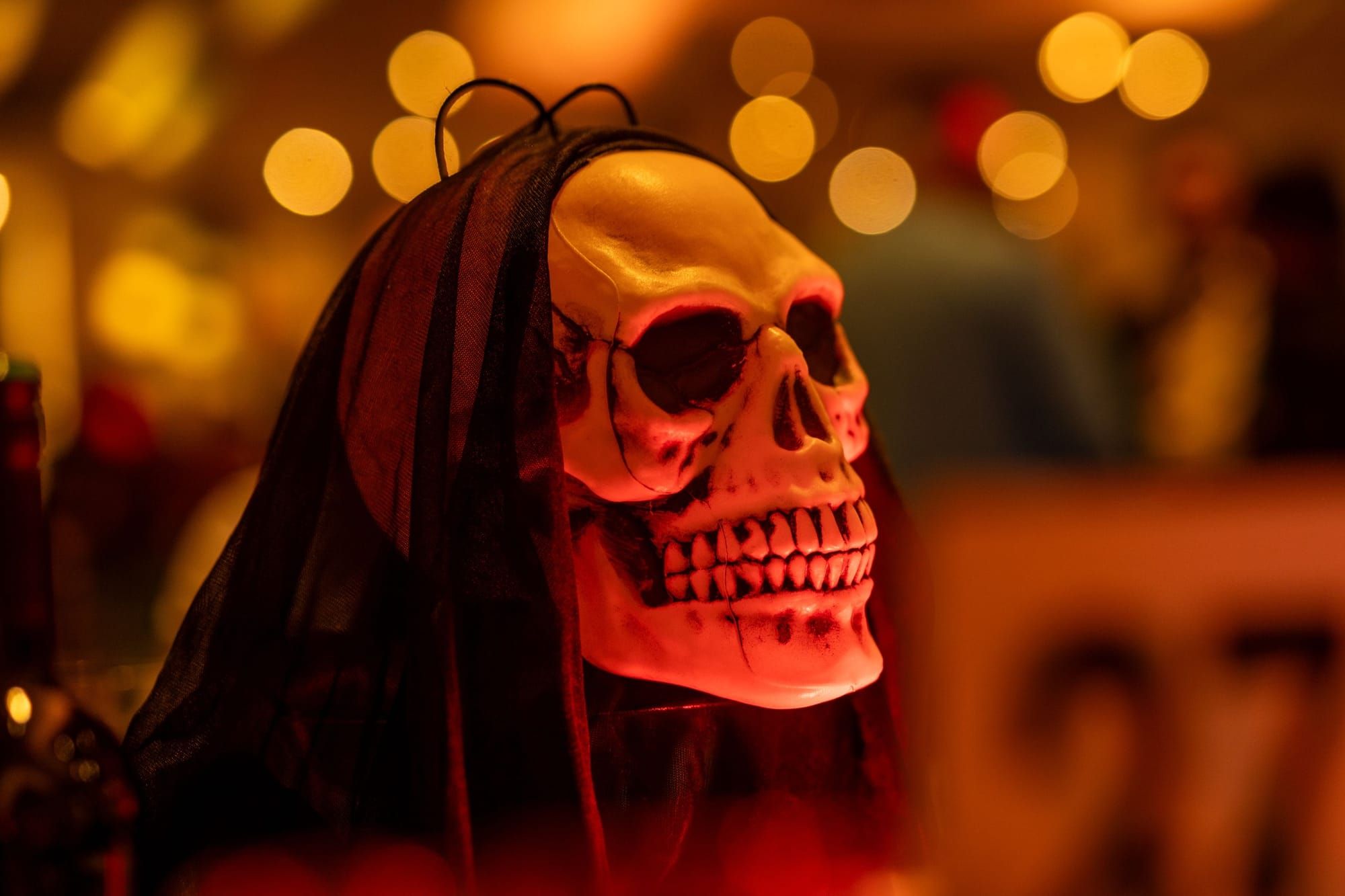 A skeleton and carved pumpkin centrepiece lit red on a Halloween dinner table