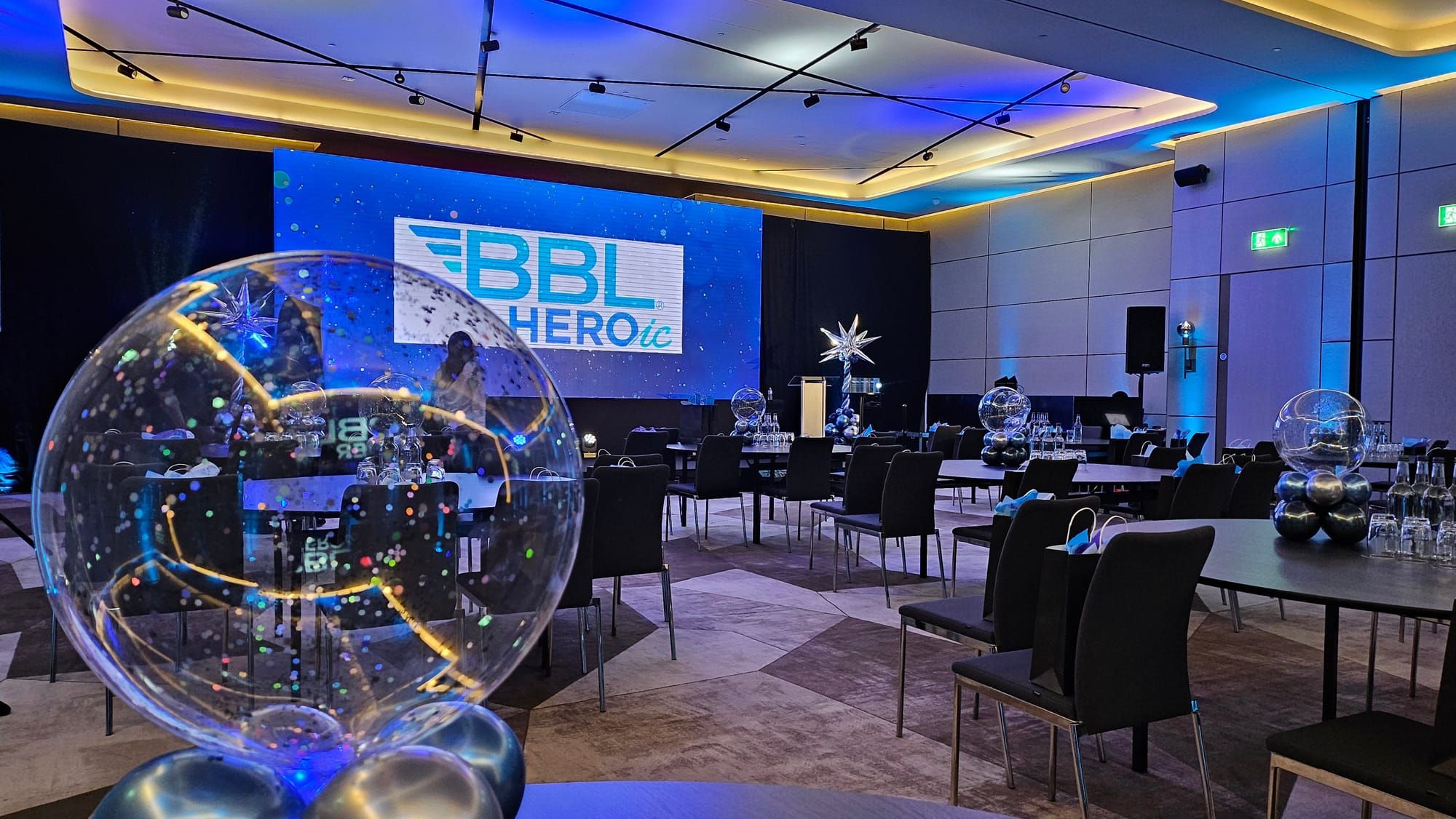 A conference room set theatre style with a branded screen and blue uplighting