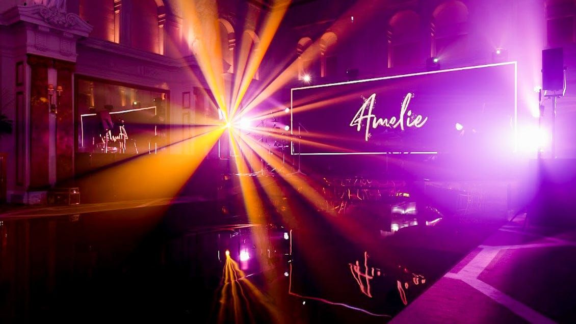 Beams of purple and amber light crossing a high-ceilinged hall