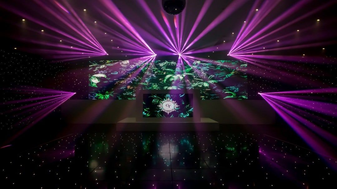 Beams and a green gobo pattern thrown across a dancefloor under a starcloth