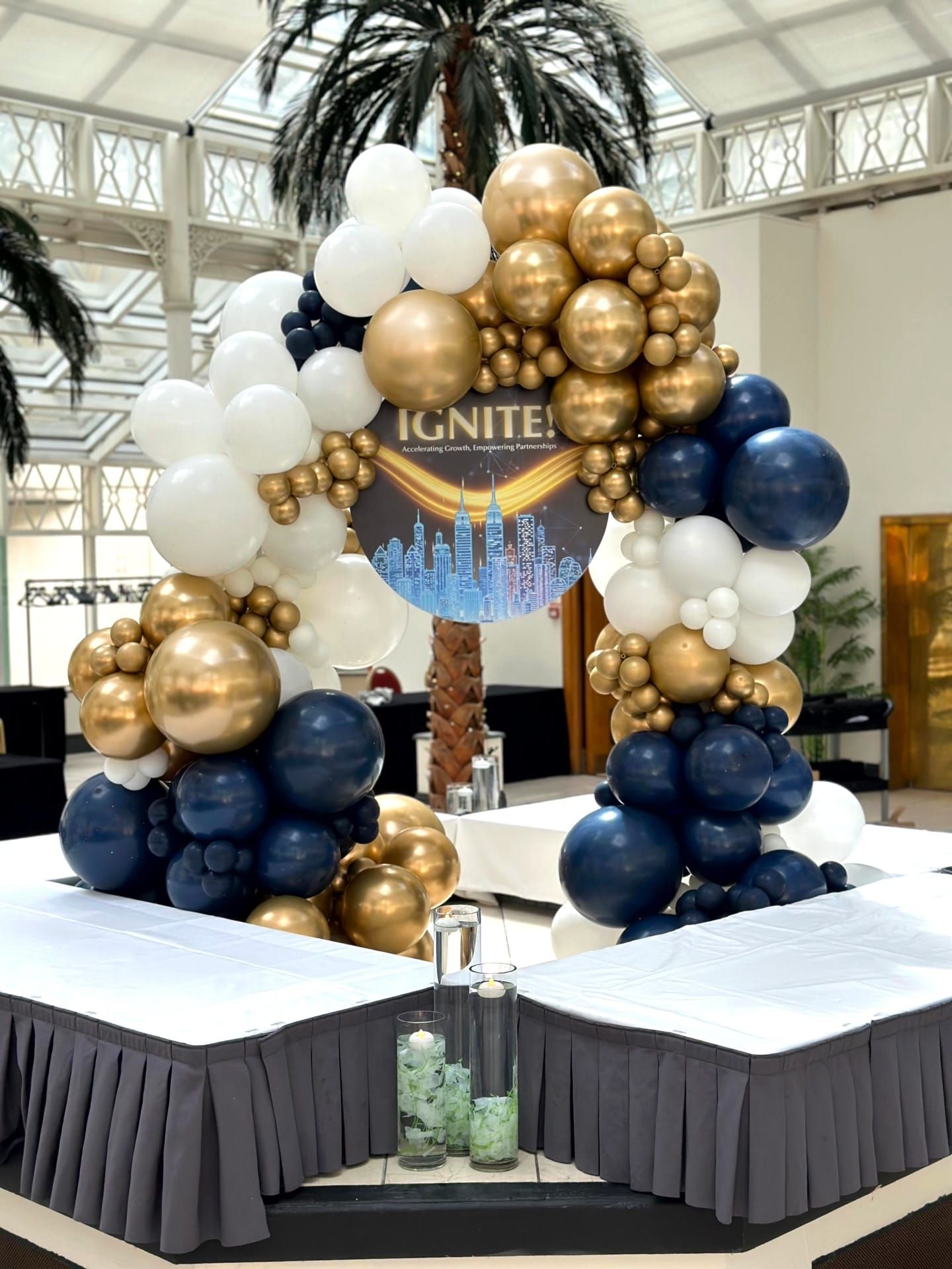 A navy and gold balloon arch framing a printed event sign