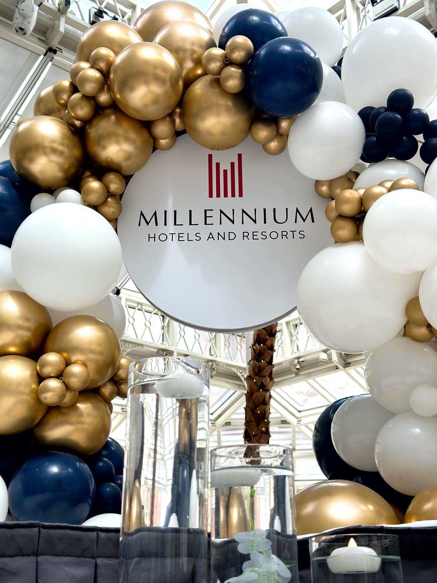 A printed brand disc suspended in an arch of white and gold balloons