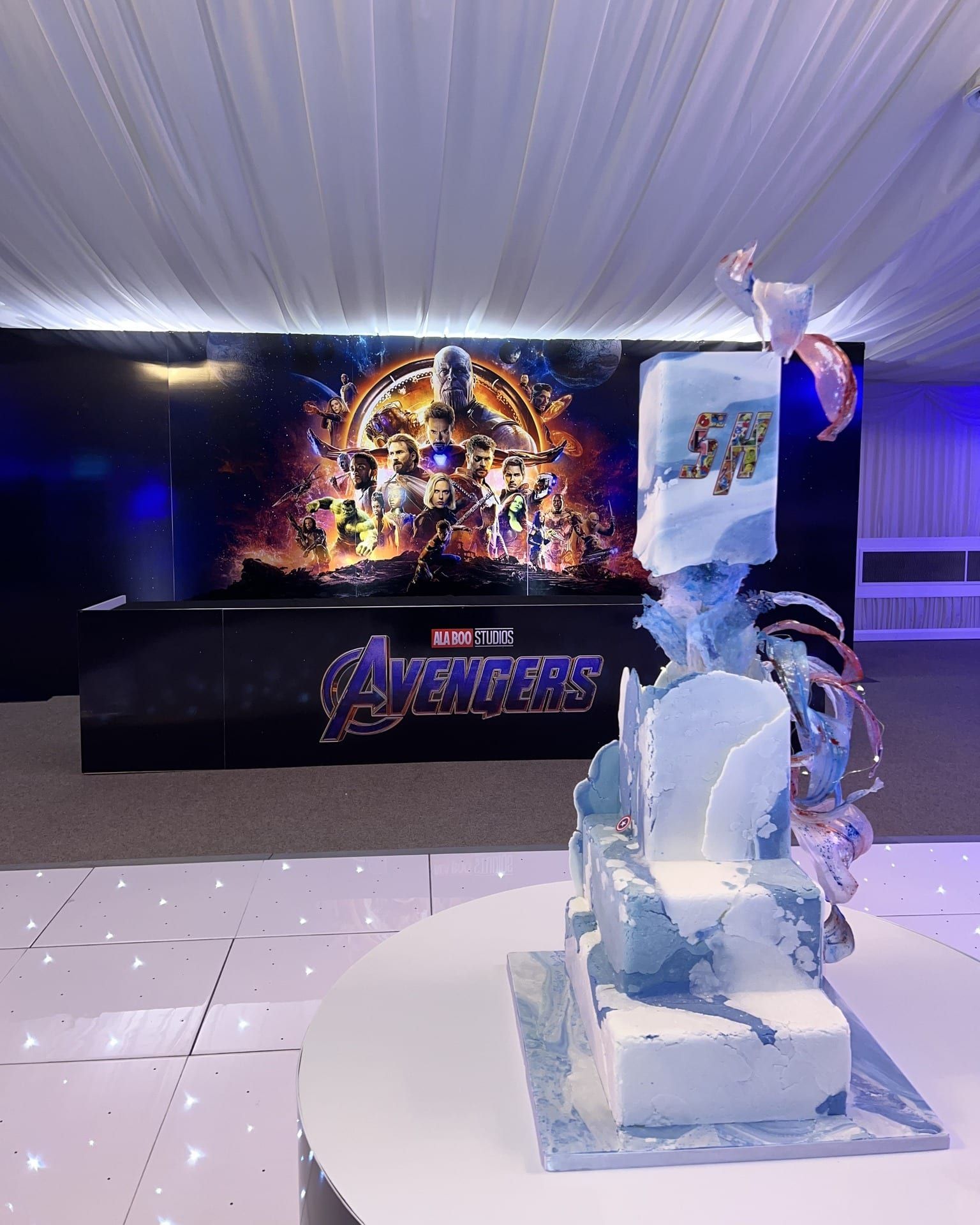A printed film backdrop and a carved ice sculpture flanking a bar