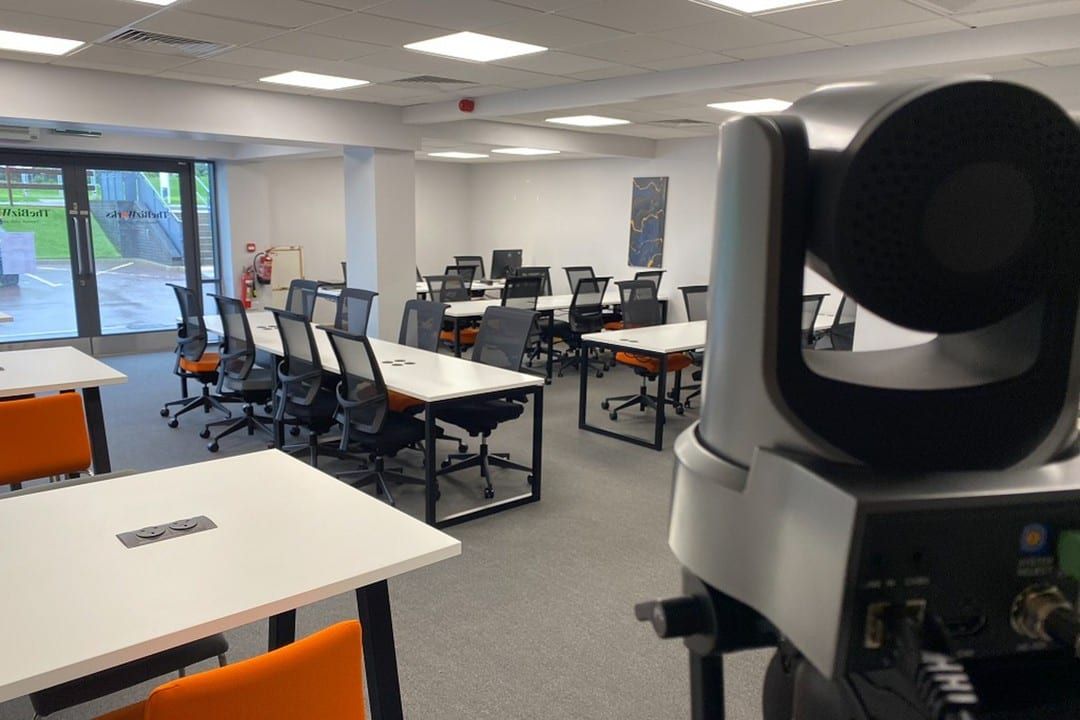 A training room fitted with desks and a broadcast camera