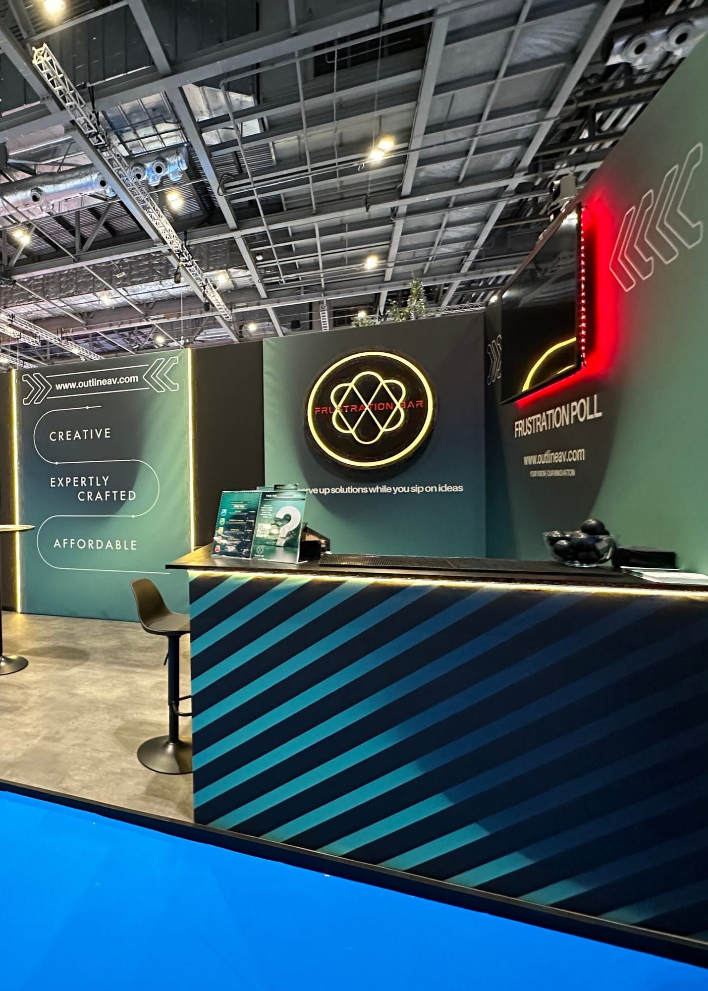 A custom-built exhibition stand with CNC-cut branding and a striped counter