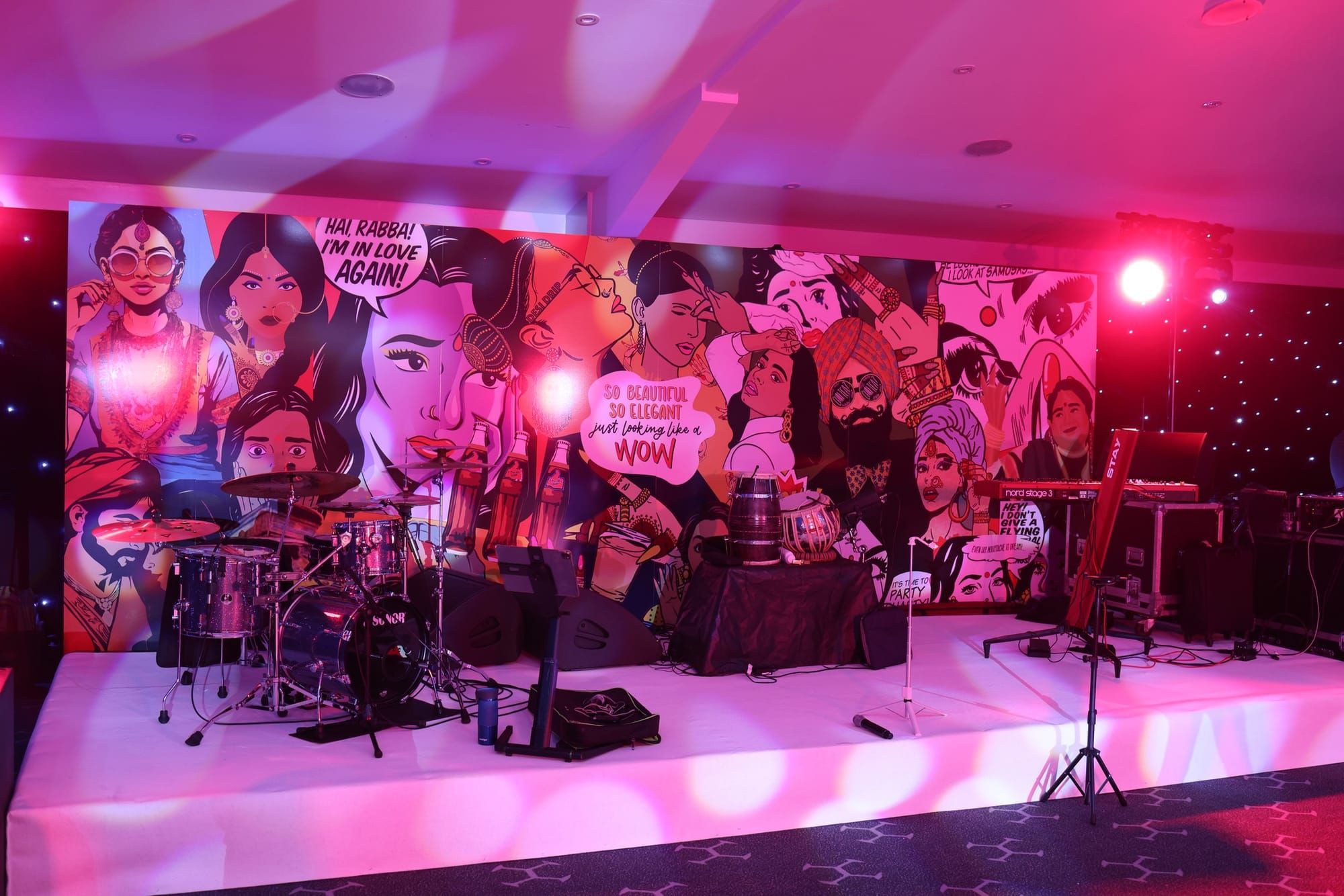 A stage set with a printed mural backdrop, drum kit and band equipment in place