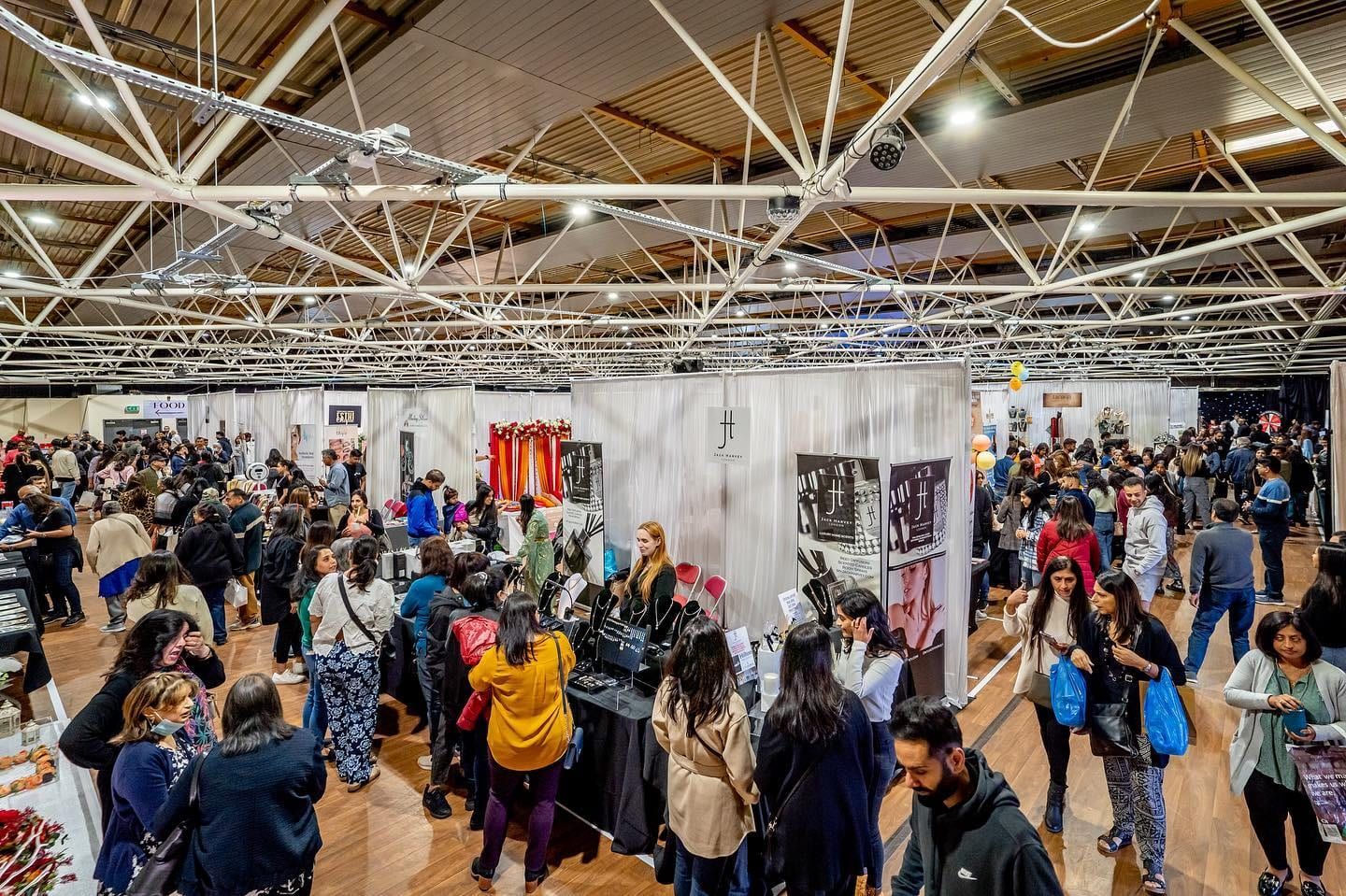 Visitors filling the aisles of a trade exhibition beneath a vaulted roof