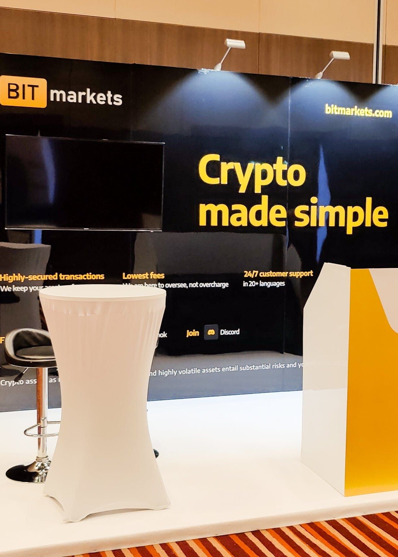 An exhibition stand with a large screen and a fitted counter