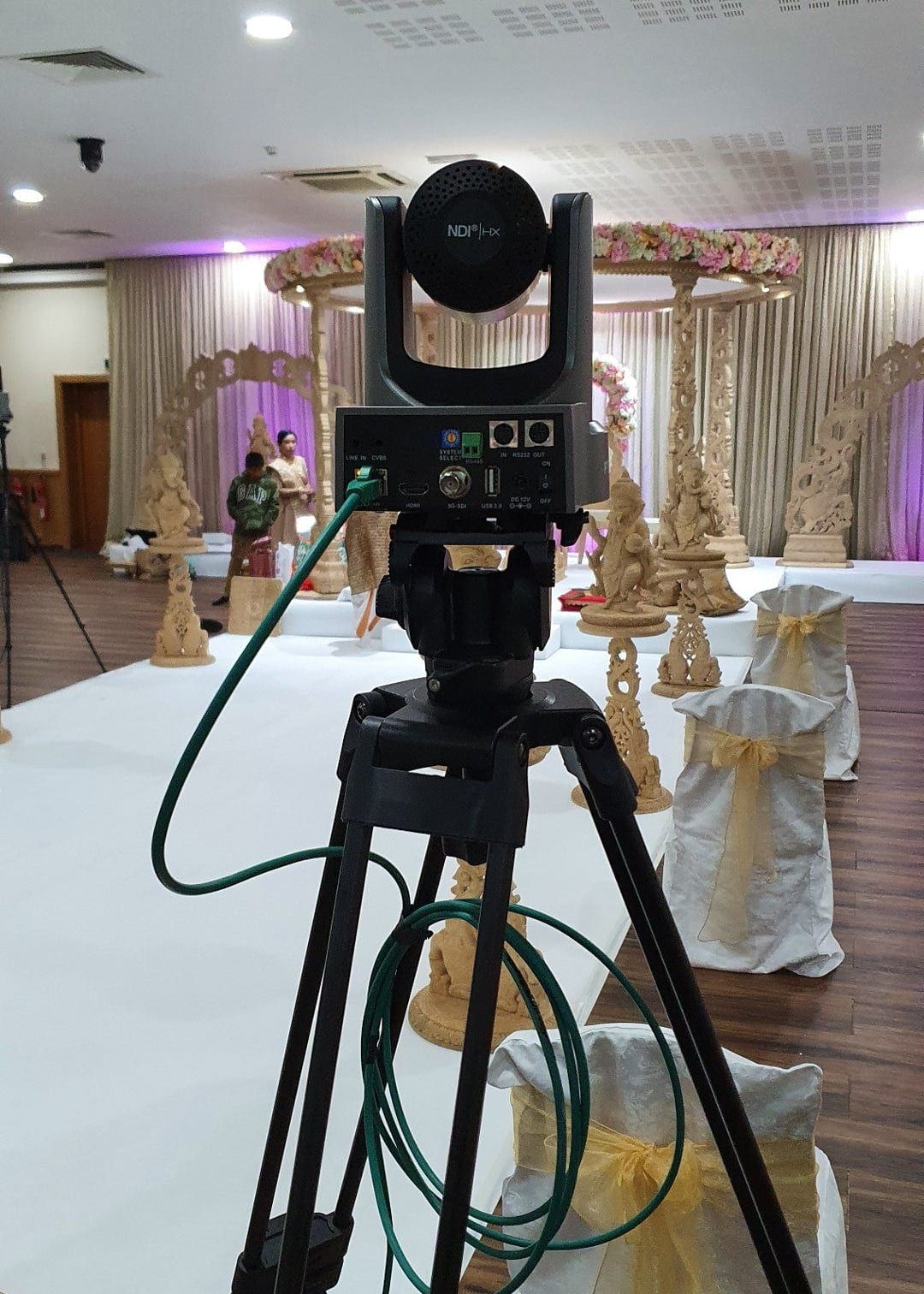 A broadcast camera on a tripod trained on the mandap before the ceremony