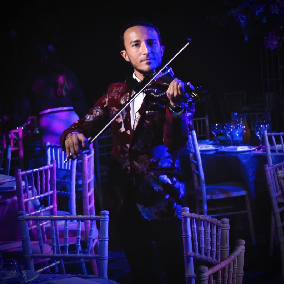 A violinist playing in a blue-lit room during dinner