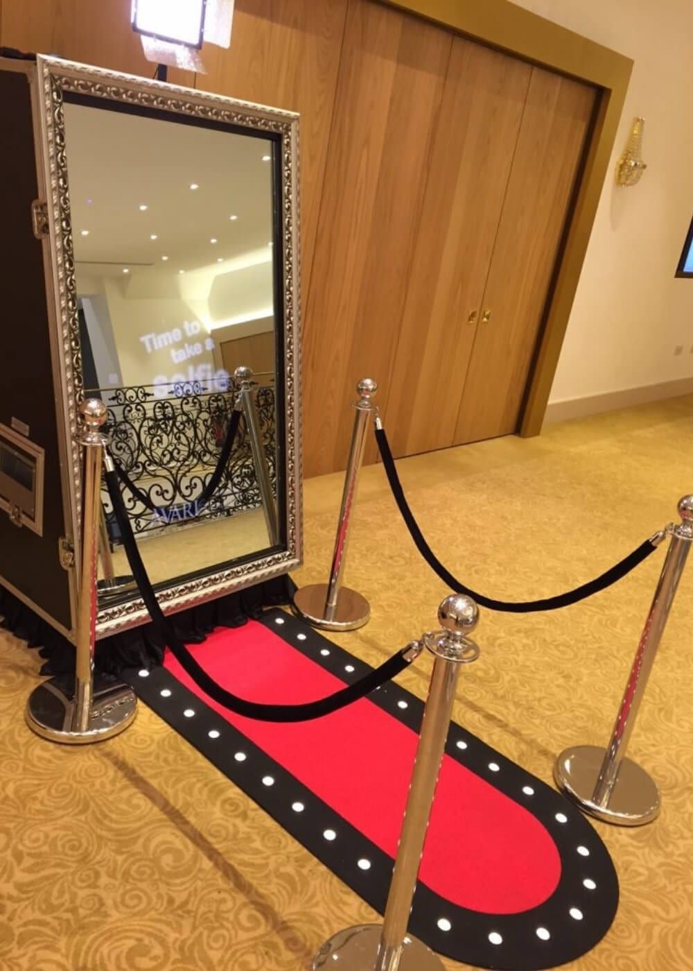 A mirror booth behind a rope barrier with red carpet laid to its base
