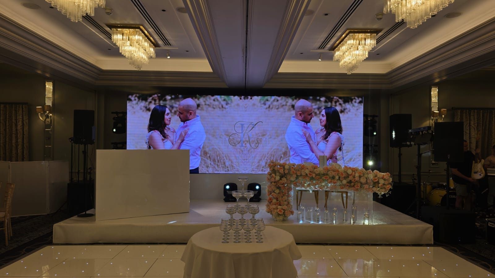 A Sopwell House ballroom with a floral top table and the couple's photograph on screen