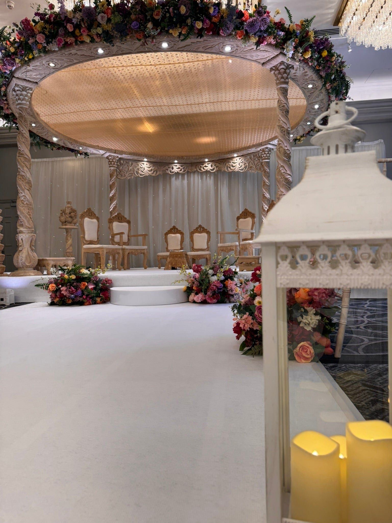 A white stage with gold chairs and florals set before the fireplace at Sopwell House