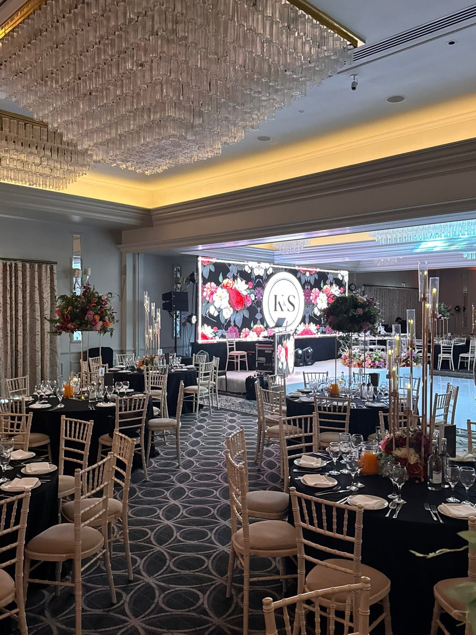 Round tables facing a floral LED backdrop carrying the couple's initials