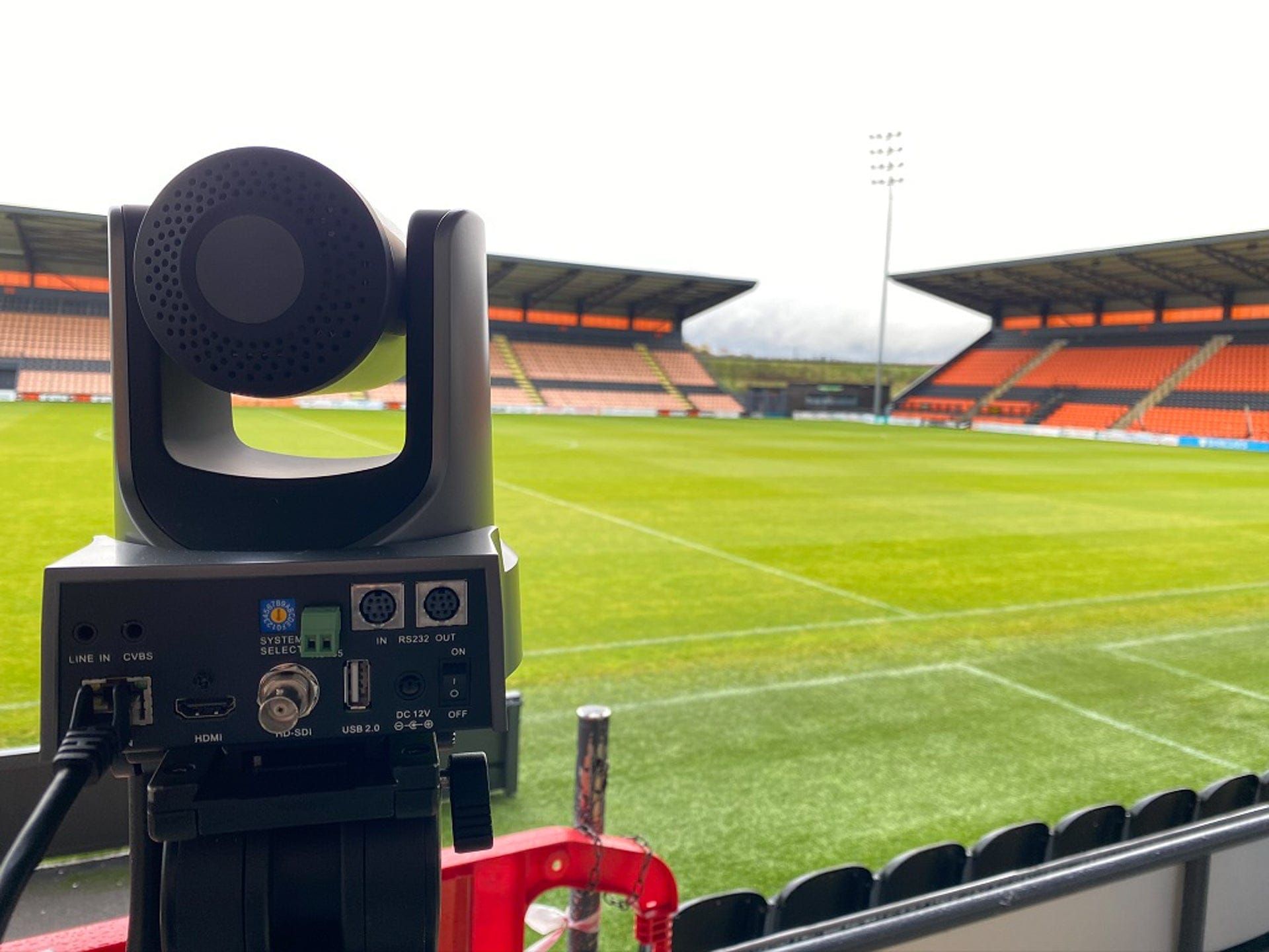 A broadcast camera positioned pitchside in an empty stadium