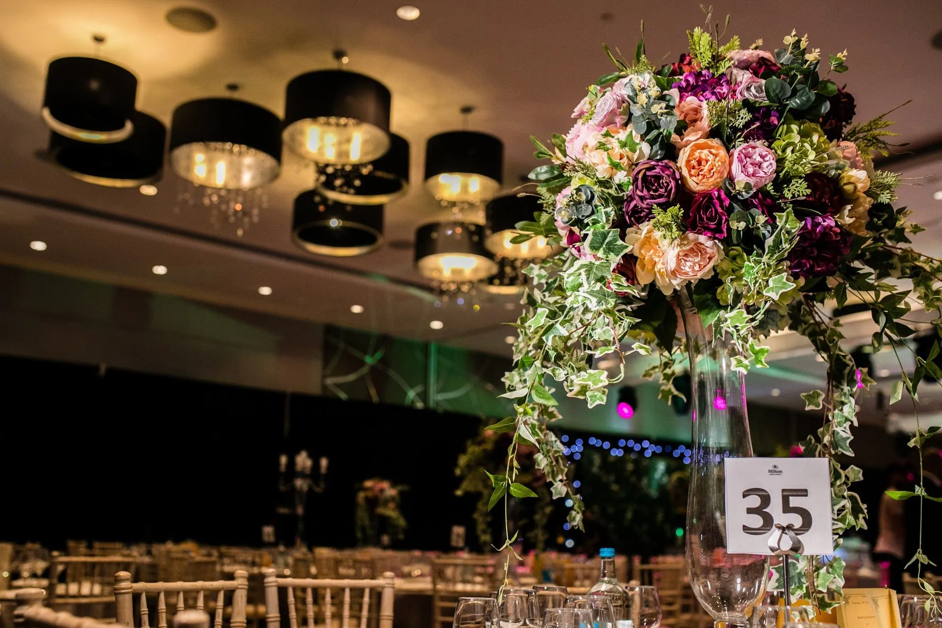 A tall rose and ivy centrepiece above a set table