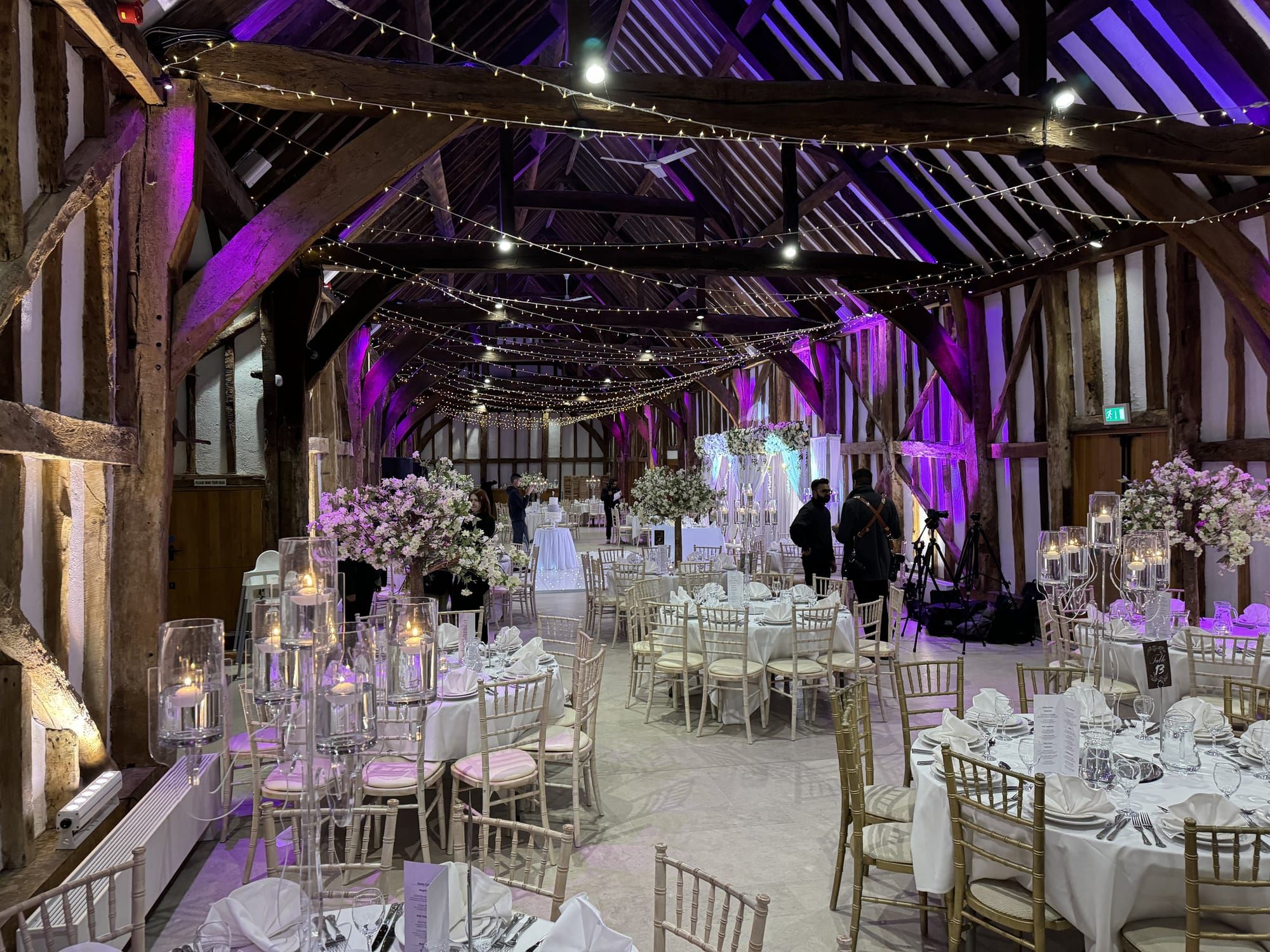 The Great Barn dressed for a wedding breakfast, fairy lights strung between the beams
