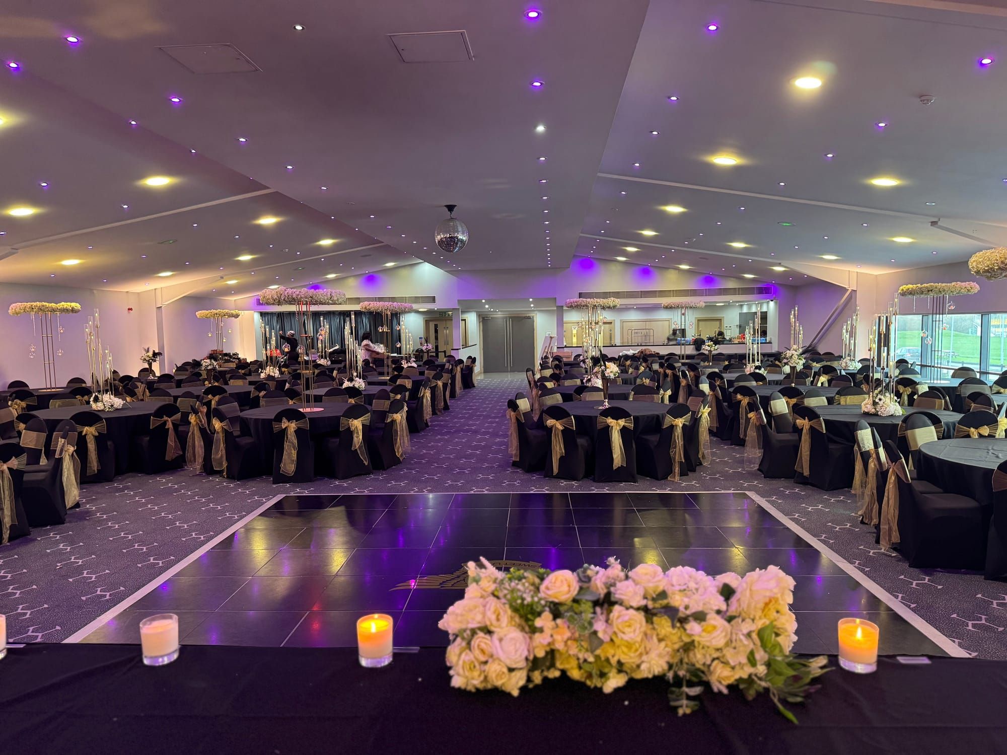 The Hive's banqueting hall with round tables, gold sashes and a central dancefloor