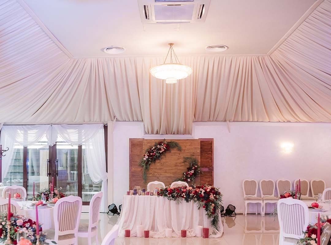 Cream drapes gathered to a central pendant and run down the walls above a floral top table